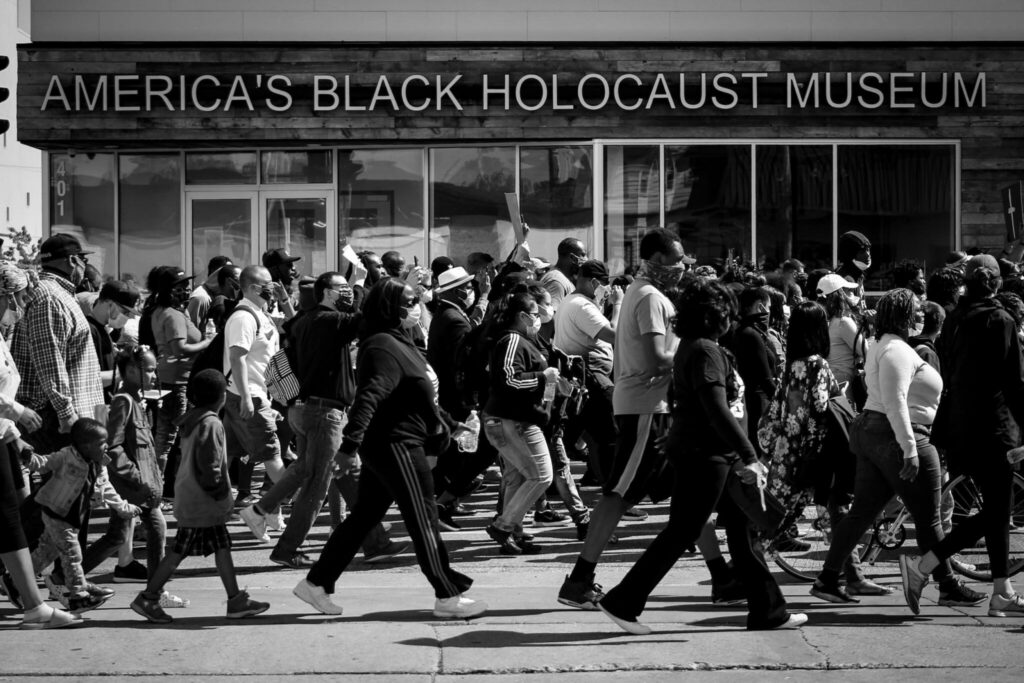 Community members marching in the street in front of America's Black Holocaust Museum in Milwaukee.
