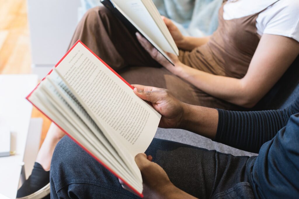 Two people sitting with books open on their laps and reading