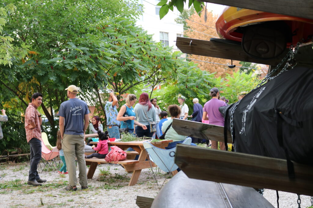 Community members gathered at Turtle Park talking, sharing food, and making flower crowns