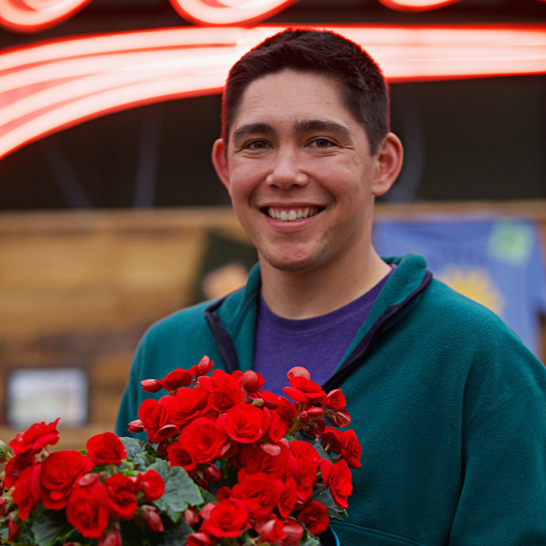 Julius Gayo smiling while holding red flowers